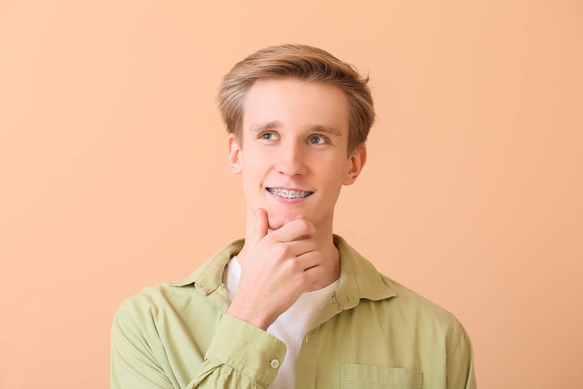A young man with braces, seen at Carpinello Orthodontics in Drexel Hill, PA, stands contemplative.