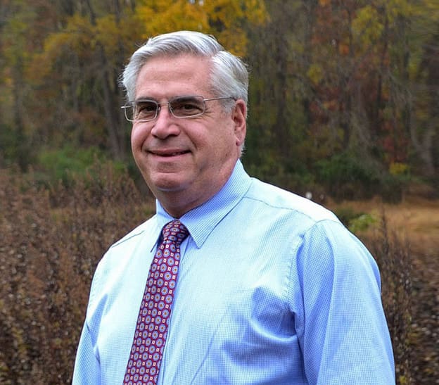 Dr. Paul Carpinello of Carpinello Orthodontics in Drexel Hill, Newtown Square or Edgmont, PA stands outdoors before autumn trees.