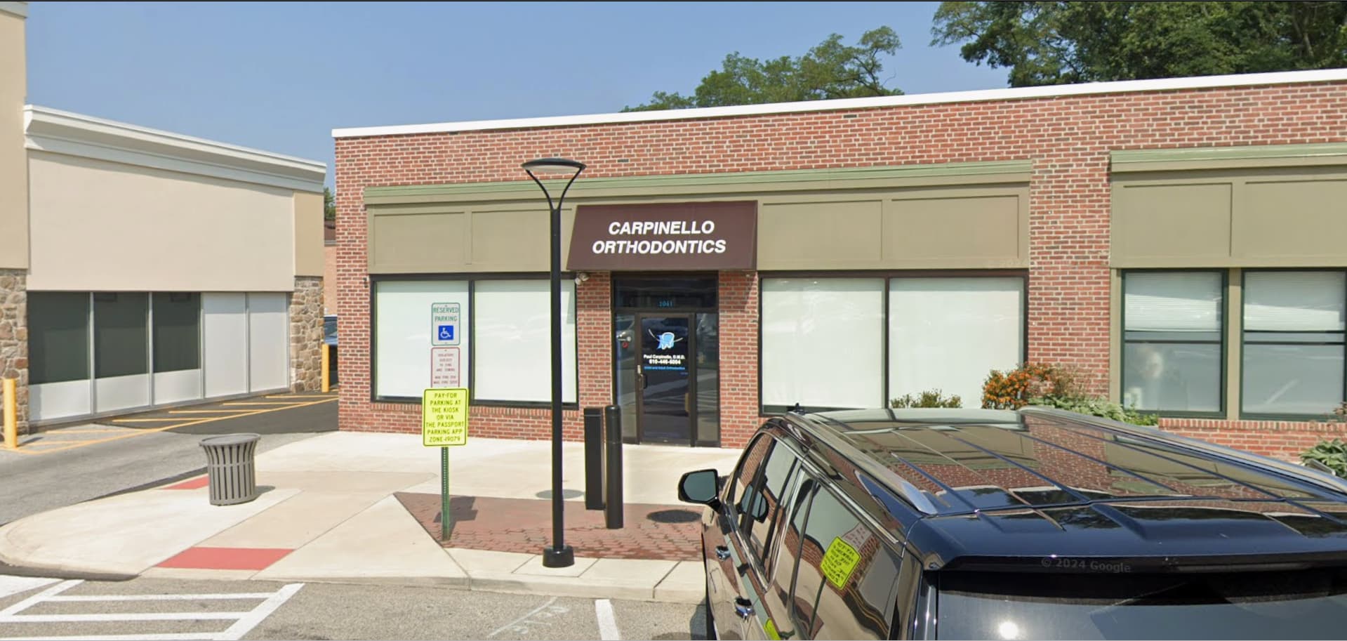 A brick building with "Carpinello Orthodontics" signage in Drexel Hill, Newtown Square and Edgmont, PA, plus parking spaces.