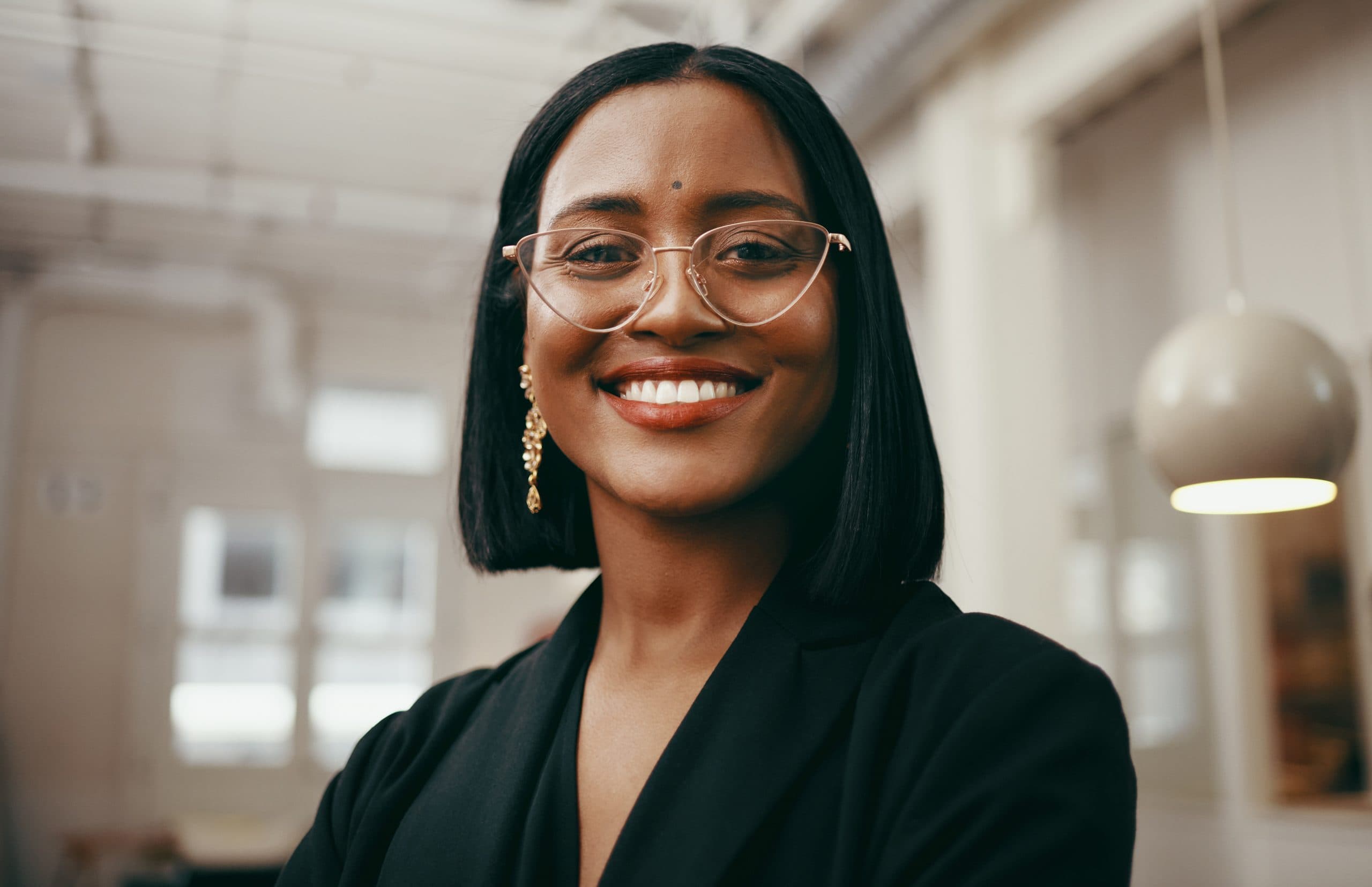 Smiling woman with short black hair and glasses shows her Invisalign smile at Carpinello Orthodontics in Drexel Hill, PA.