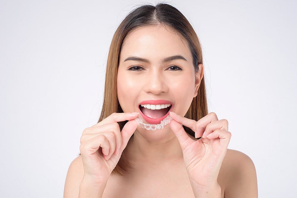 A woman prepares to place Invisalign® Clear Aligners from Carpinello Orthodontics in Newtown Square, PA.