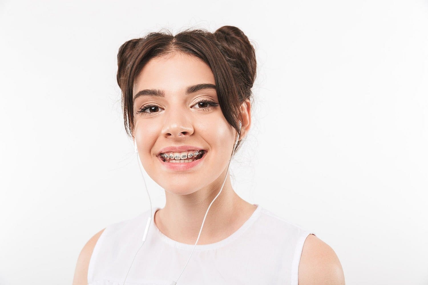 Smiling teen girl with dark hair in buns and metal braces from Carpinello Orthodontics in Newtown Square, PA.