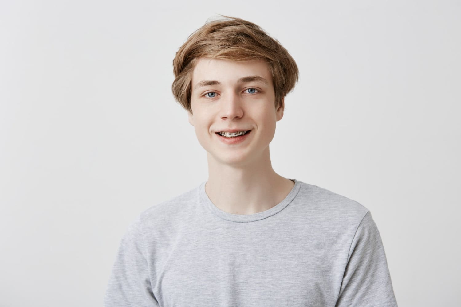 A teenage boy with metal braces, treated at Carpinello Orthodontics in Drexel Hill, PA, stands facing the camera.