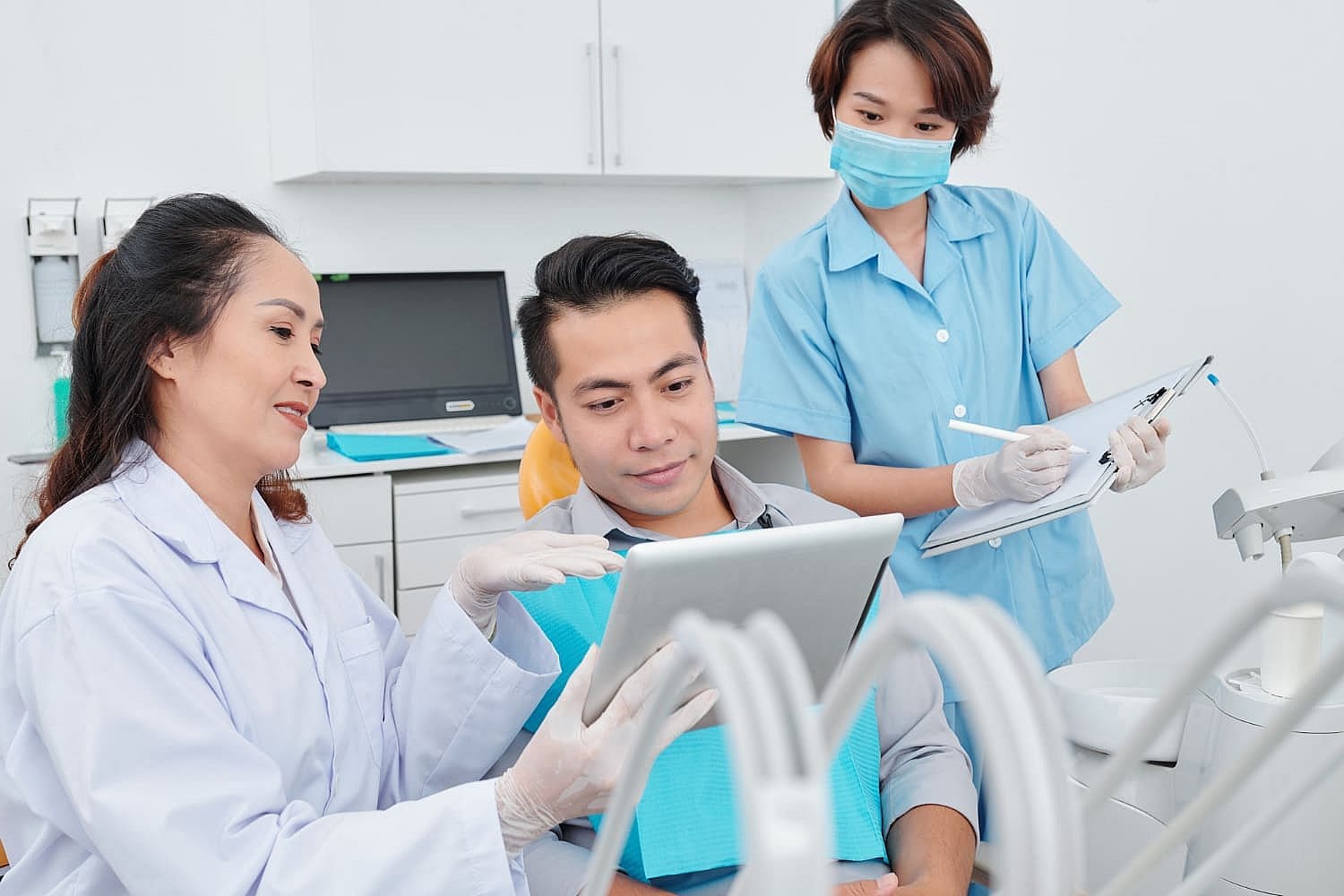 At Carpinello Orthodontics in Drexel Hill, PA, an Orthodontist consults with a patient on a tablet as an assistant takes notes.