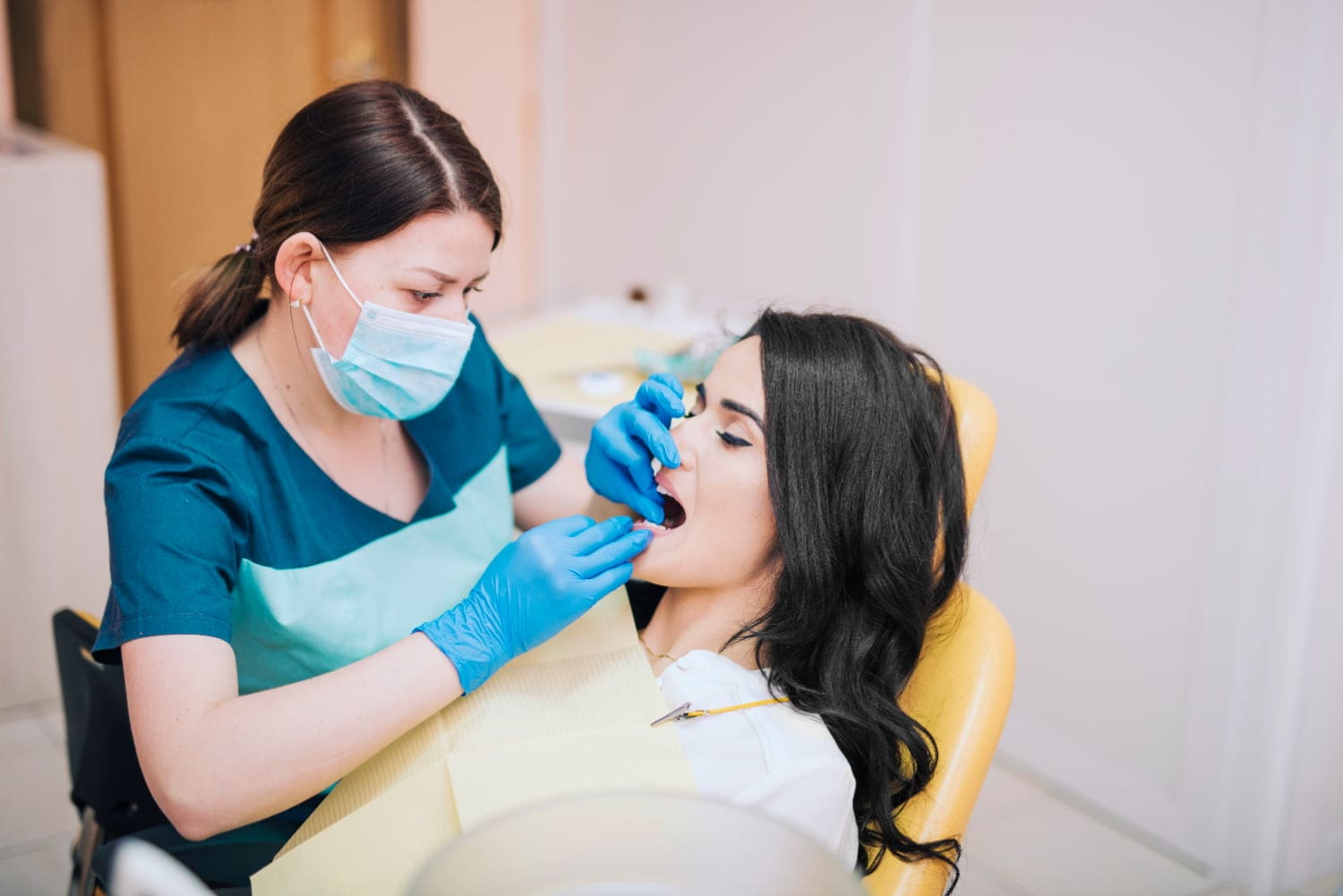 A dentist in gloves and mask examines a patient at Carpinello Orthodontics in Drexel Hill, Newtown Square or Edgmont, PA.