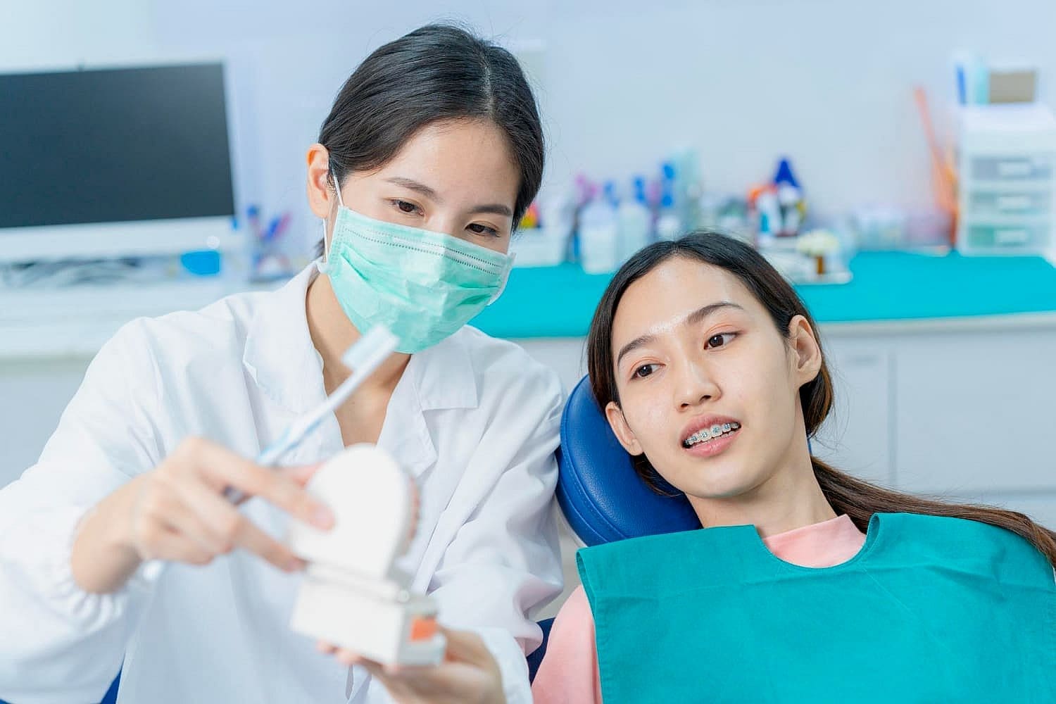 A masked dentist at Carpinello Orthodontics in Drexel Hill, Newtown Square, or Edgmont, PA shows a dental model to an adult braces patient to explain the orthodontic treatment journey.