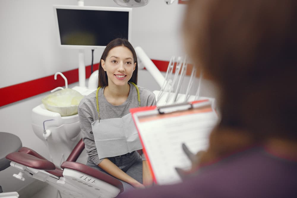 A woman smiles in a dental chair as a professional discusses orthodontic insurance at Carpinello Orthodontics in Drexel Hill, Newtown Square or Edgmont, PA.