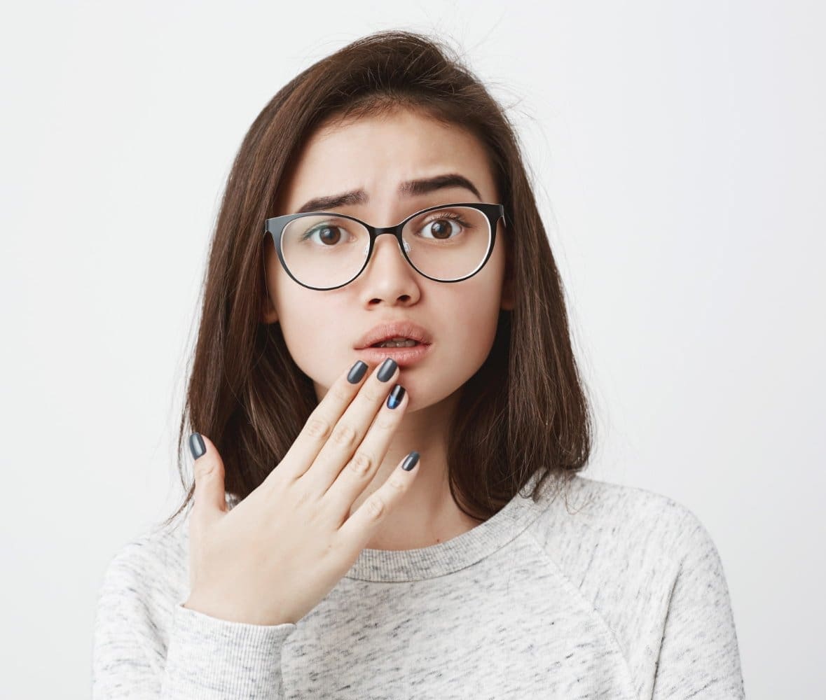 A surprised young woman covers her mouth, showing mouth breathing's link to dry mouth at Carpinello Orthodontics in Drexel Hill, Newtown Square or Edgmont, PA.