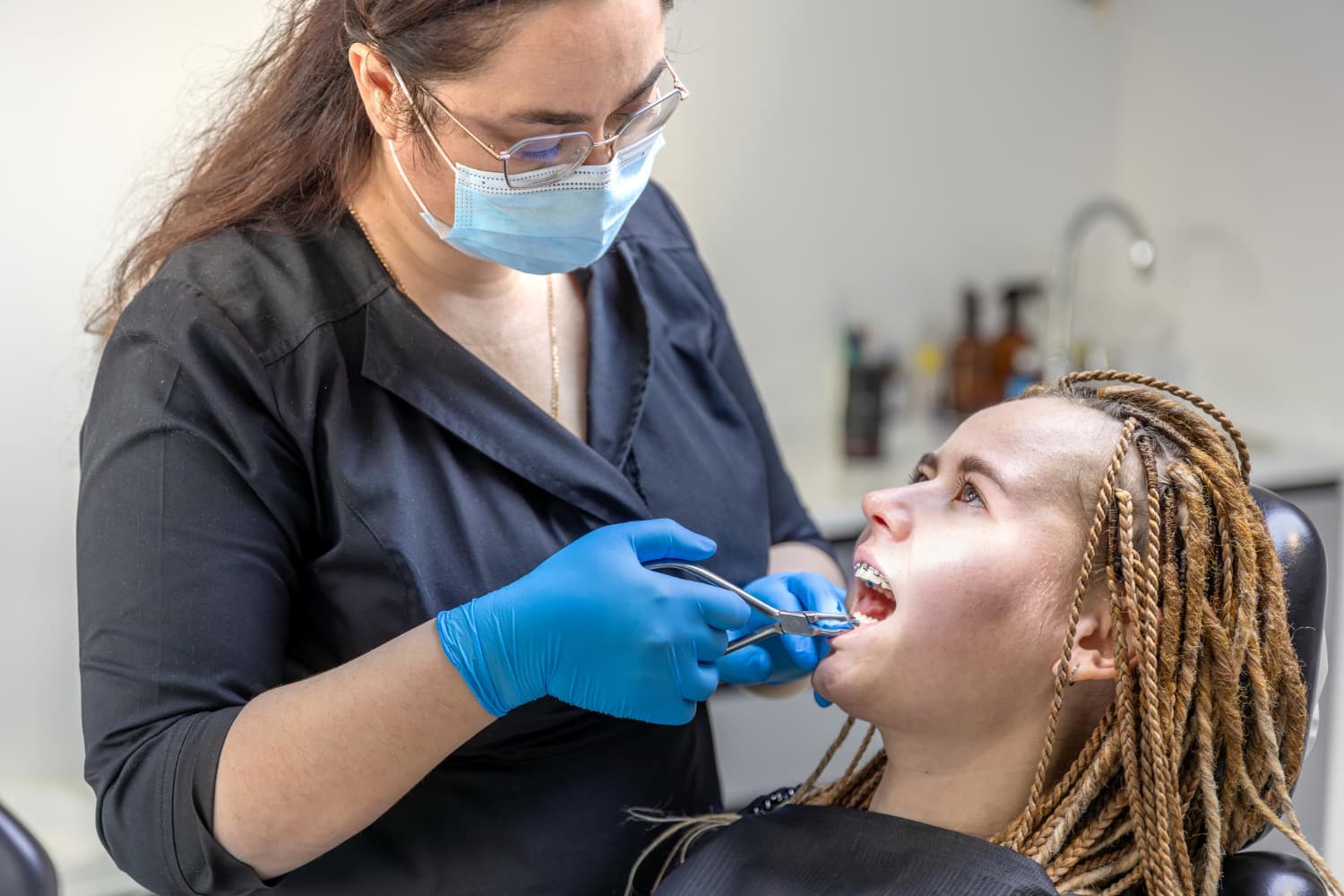 At Carpinello Orthodontics in Drexel Hill, Newtown Square or Edgmont, PA, a masked dentist checks a patient’s overbite with tools.