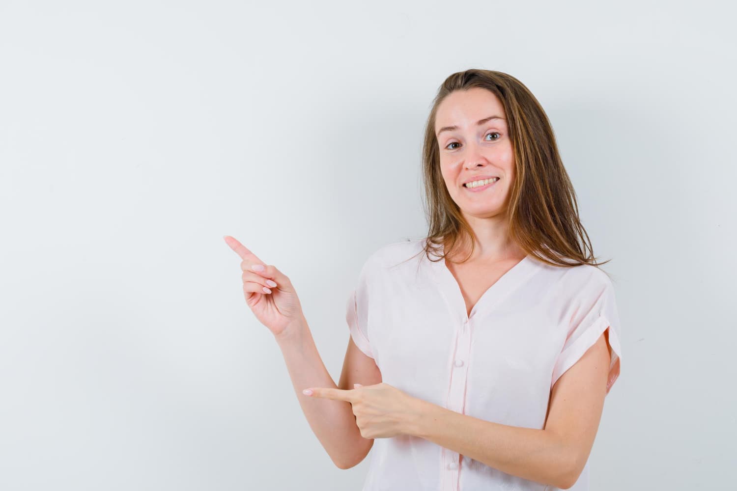 Smiling woman in a pink blouse points left, showing a slight overbite—Carpinello Orthodontics in Drexel Hill, Newtown Square or Edgmont, PA.
