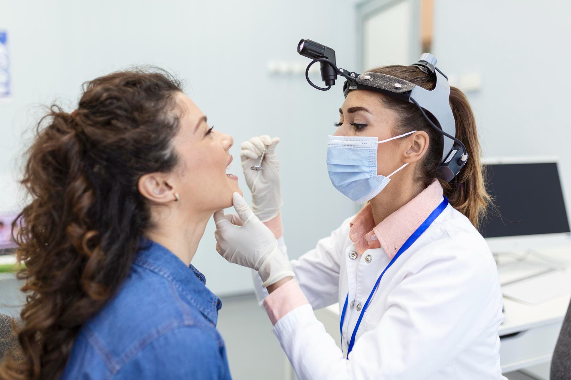 At Carpinello Orthodontics in Drexel Hill, Newtown Square or Edgmont, PA, a doctor checks a woman's throat for tongue thrust.