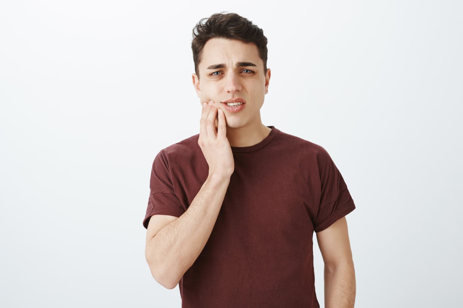Young man in pain, holding his cheek, possibly from underbite; Carpinello Orthodontics in Drexel Hill, Newtown Square or Edgmont, PA.