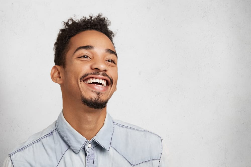 Smiling young man with curly hair and goatee, confident after mouth breather treatment at Carpinello Orthodontics in Drexel Hill, Newtown Square or Edgmont, PA.