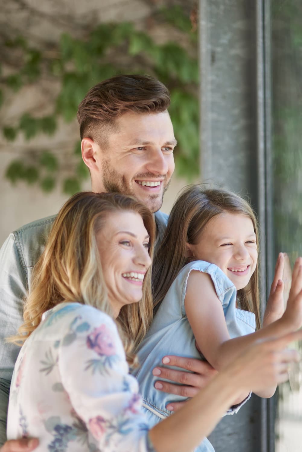 Smiling family with a man wearing adult braces looks out a window at greenery, representing Carpinello Orthodontics in Drexel Hill, Newtown Square or Edgmont, PA.