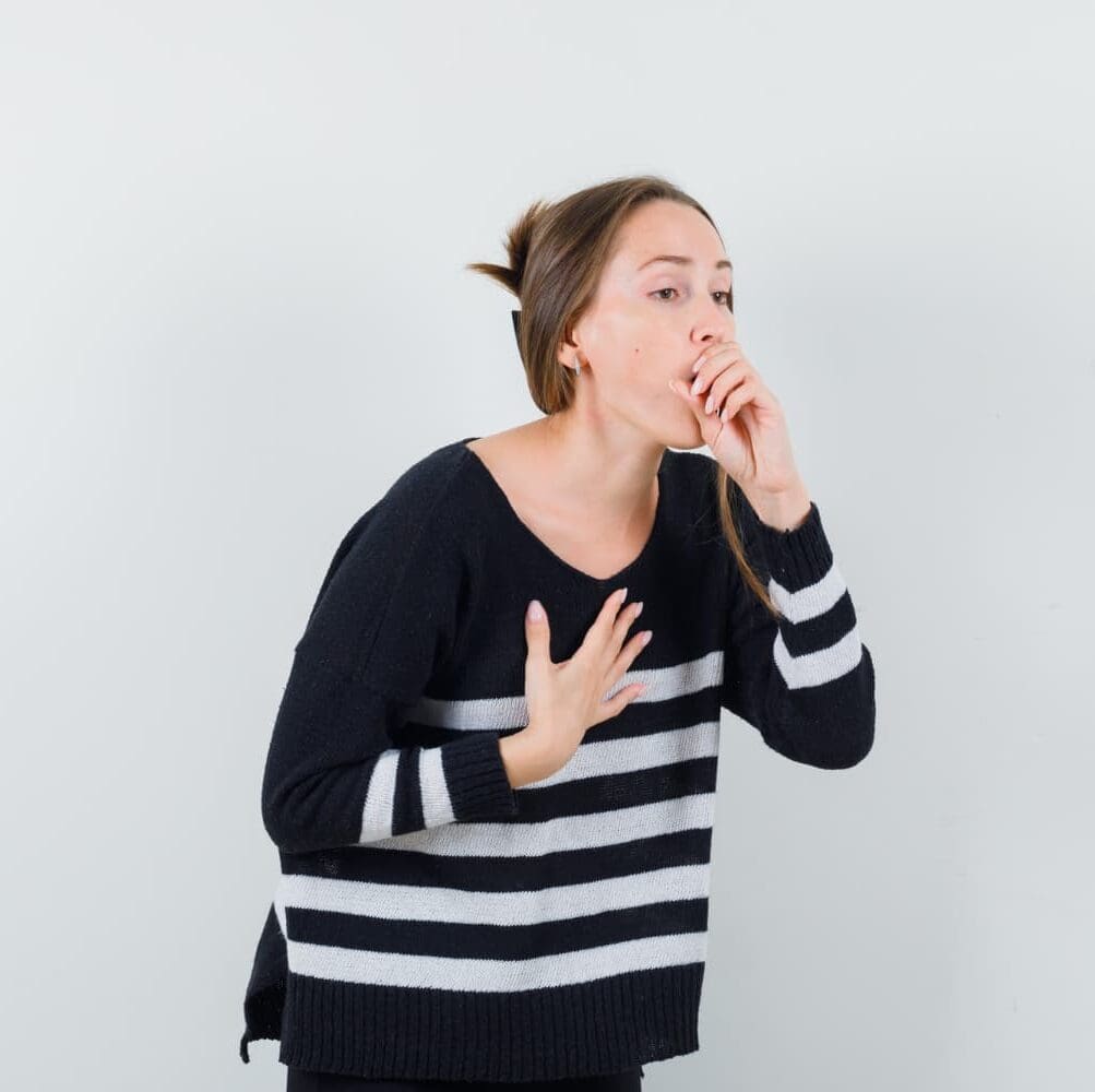 A woman coughs or feels unwell, highlighting mouth breathing issues. Carpinello Orthodontics in Drexel Hill, Newtown Square or Edgmont, PA.