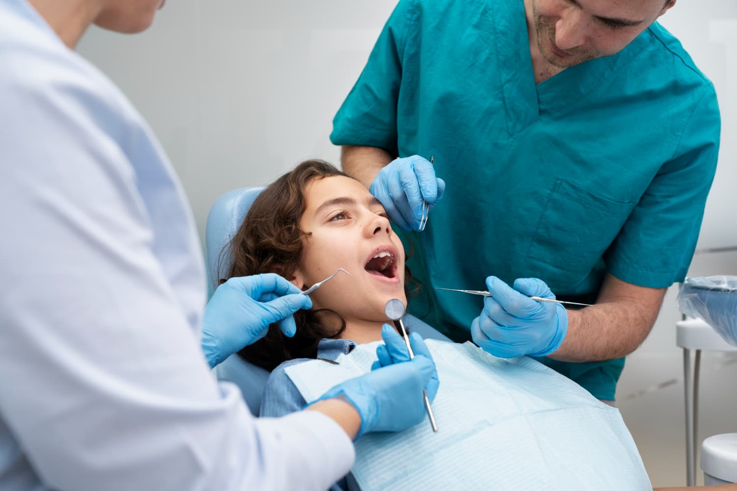 At Carpinello Orthodontics in Drexel Hill, Newtown Square or Edgmont, PA, two dentists examine a child’s open mouth for tongue thrust.