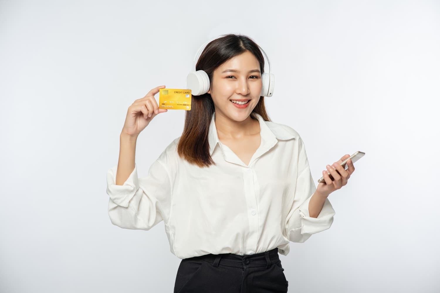 Smiling woman with headphones, credit card, and smartphone considers Invisalign at Carpinello Orthodontics in Drexel Hill, Newtown Square or Edgmont, PA.