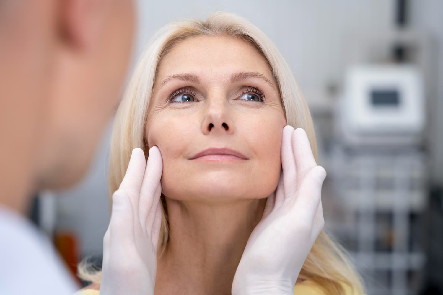 During a jaw surgery consultation at Carpinello Orthodontics in Drexel Hill, Newtown Square or Edgmont, PA, a doctor gently examines a woman's face.