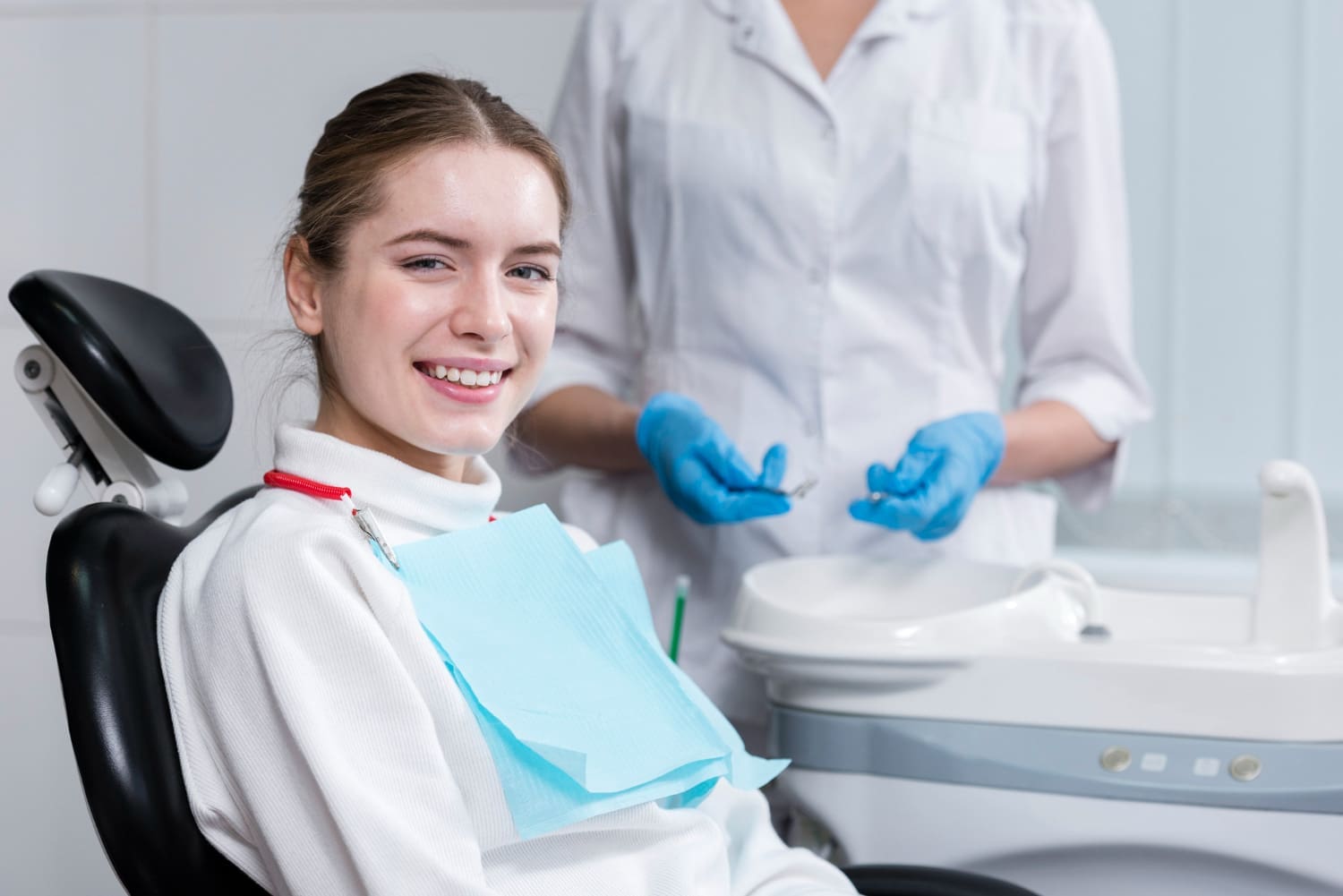 A woman smiles in a dental chair at Carpinello Orthodontics in Drexel Hill, Newtown Square or Edgmont, PA as a dentist prepares to discuss braces insurance.
