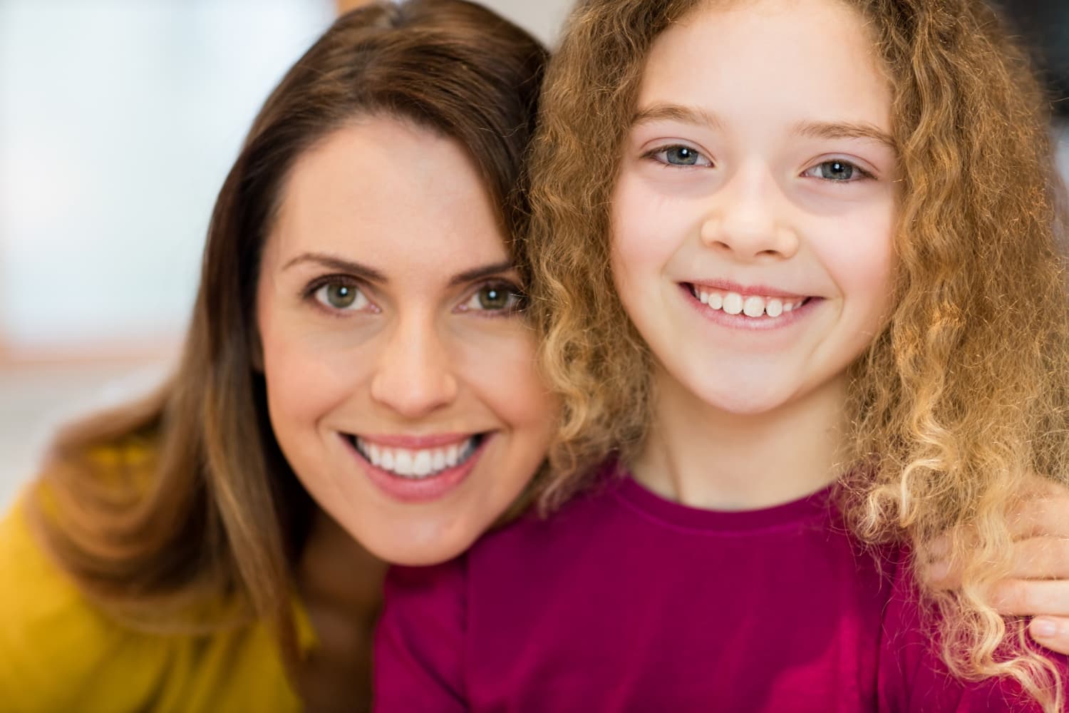 Smiling woman and girl with curly hair, girl's palate expander visible, at Carpinello Orthodontics in Drexel Hill, Newtown Square or Edgmont, PA.