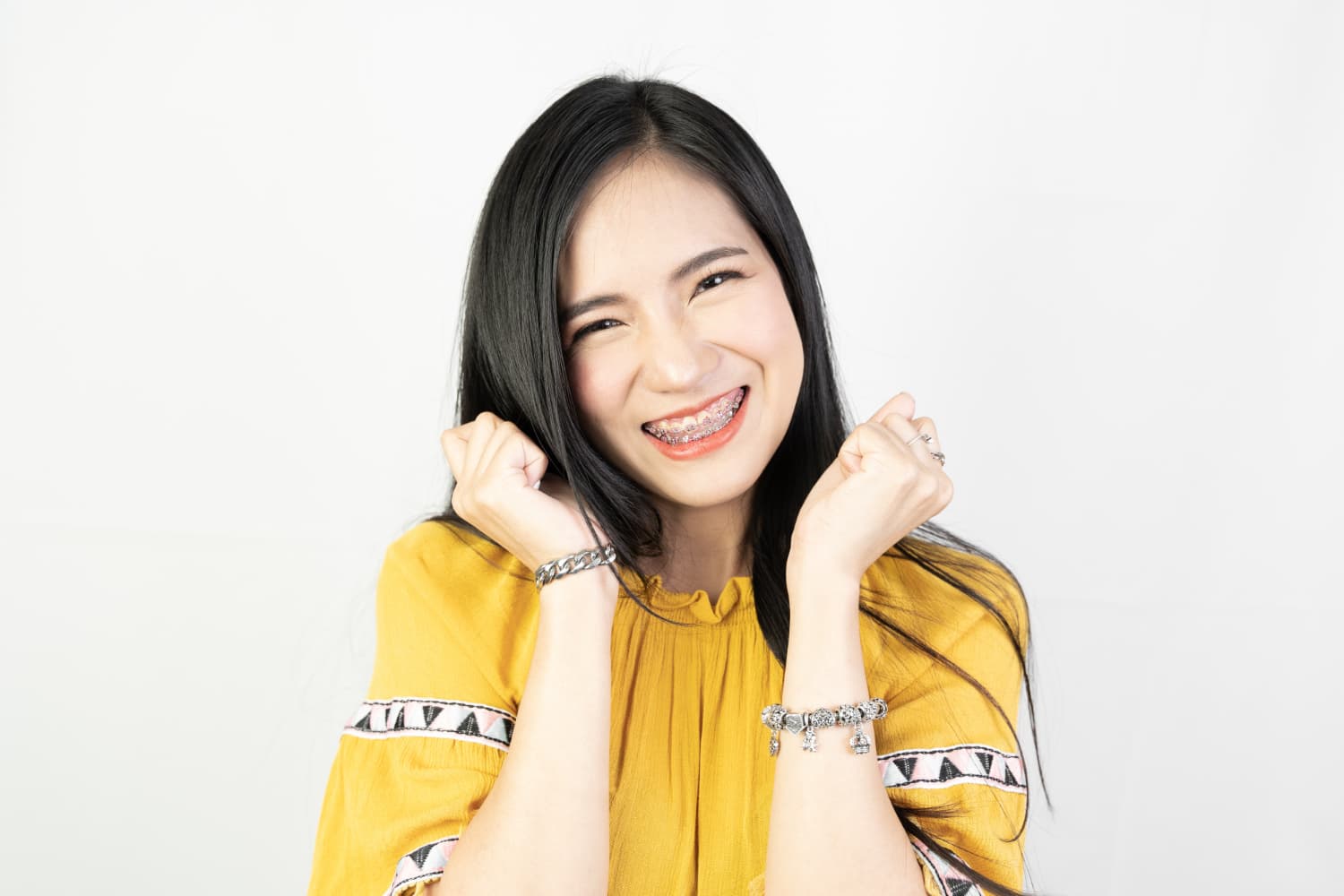 A woman with braces smiles joyfully, celebrating insurance news for Carpinello Orthodontics in Drexel Hill, Newtown Square or Edgmont, PA.