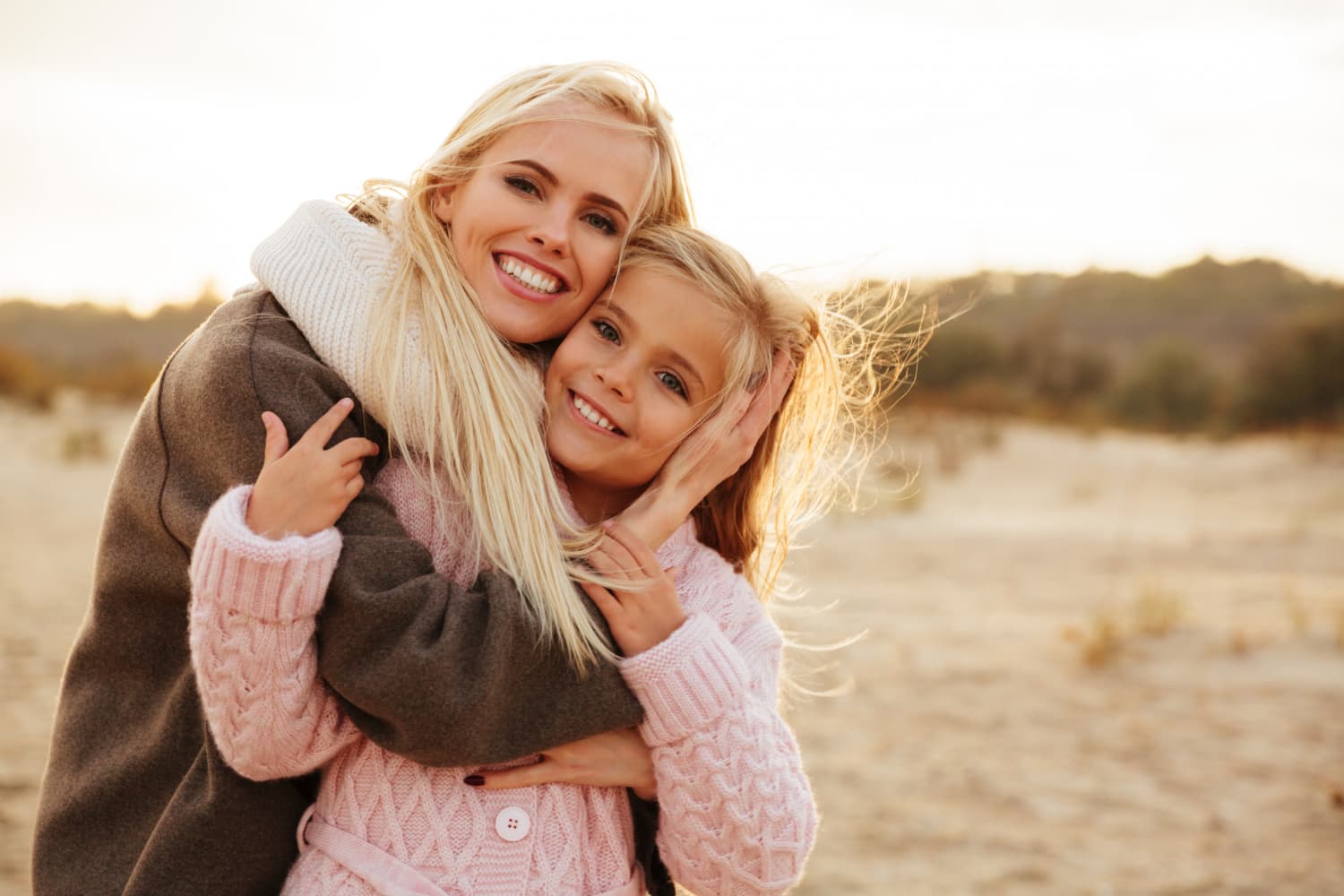 Smiling with metal braces, a woman and girl hug outdoors, showing joy at Carpinello Orthodontics in Drexel Hill, Newtown Square or Edgmont, PA.