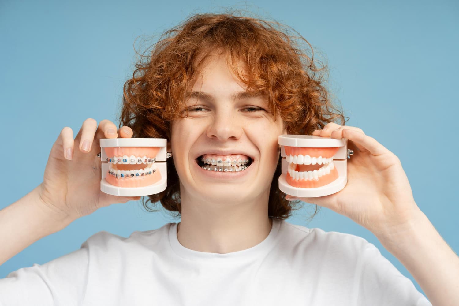 A smiling person with braces displays dental models, illustrating Carpinello Orthodontics for adults in Drexel Hill, Newtown Square or Edgmont, PA.