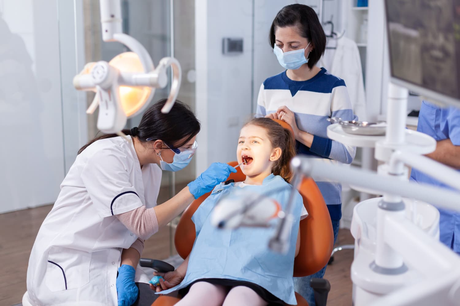 At Carpinello Orthodontics in Drexel Hill, Newtown Square or Edgmont, PA, a masked dentist checks a girl for tongue thrust.