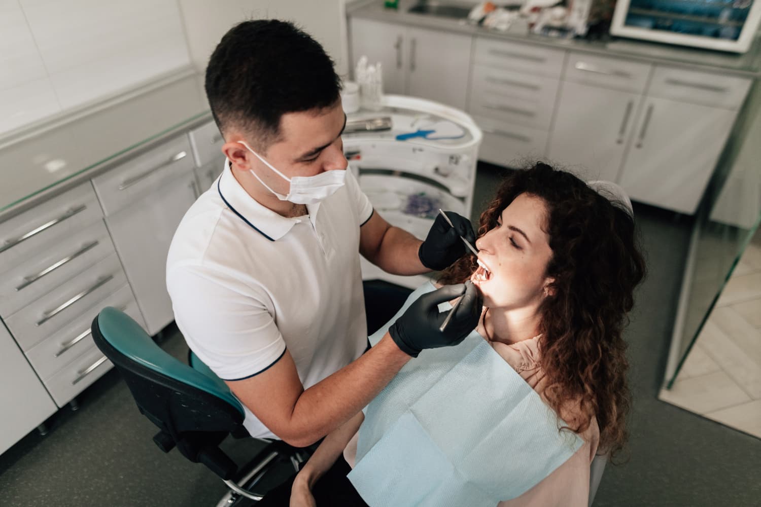 At Carpinello Orthodontics in Drexel Hill, Newtown Square or Edgmont, PA, a dentist checks a female patient’s teeth for tongue thrust.