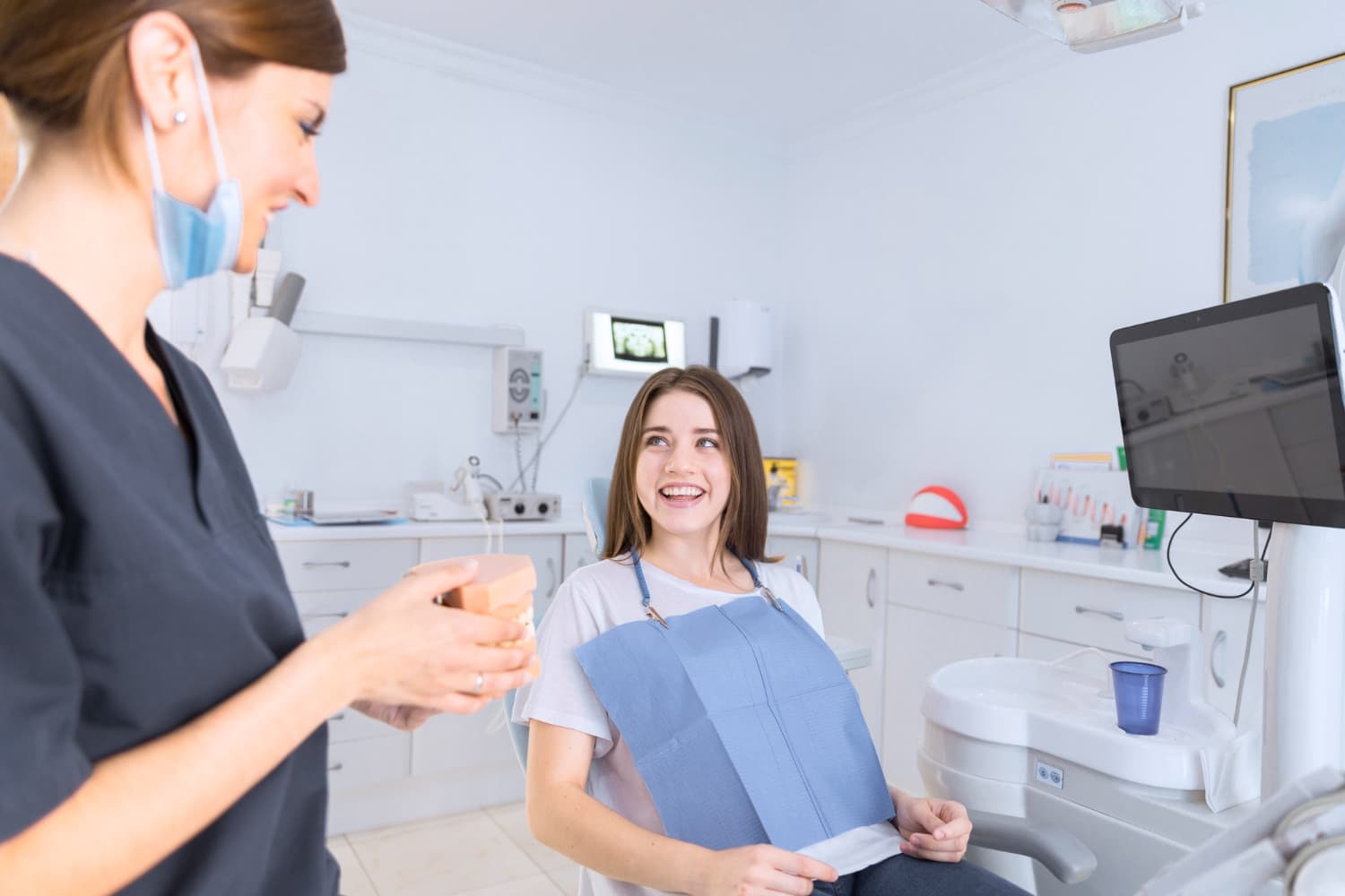 At Carpinello Orthodontics in Drexel Hill, Newtown Square or Edgmont, PA, a dental professional reviews Invisalign payment plans with a smiling patient.