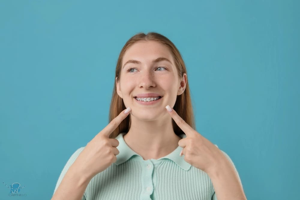 A smiling girl holds and points to an Invisalign Teen aligner with Carpinello Orthodontics in Drexel Hill, Newtown Square or Edgmont, PA, on a blue background. A smiling girl holds and points to an Invisalign Teen aligner with Carpinello Orthodontics in Drexel Hill, Newtown Square or Edgmont, PA, on a blue background.